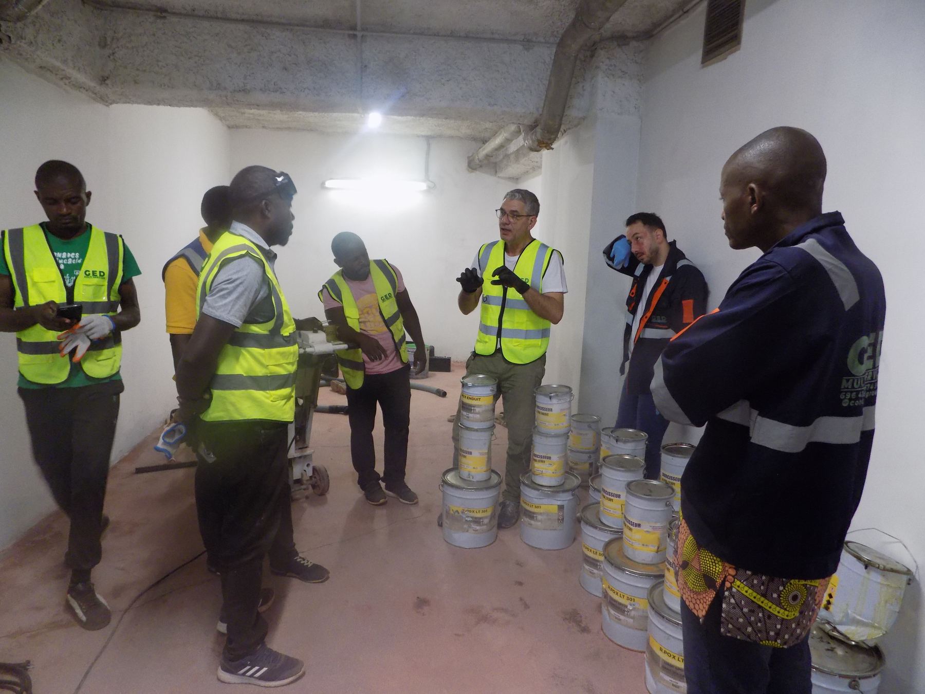 Équipe GED en session technique avec un formateur, autour des fûts de résine