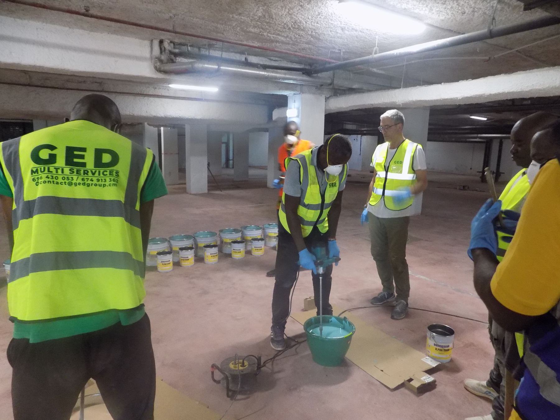 Ouvrier GED mélangeant une résine bi-composant sur un chantier de parking